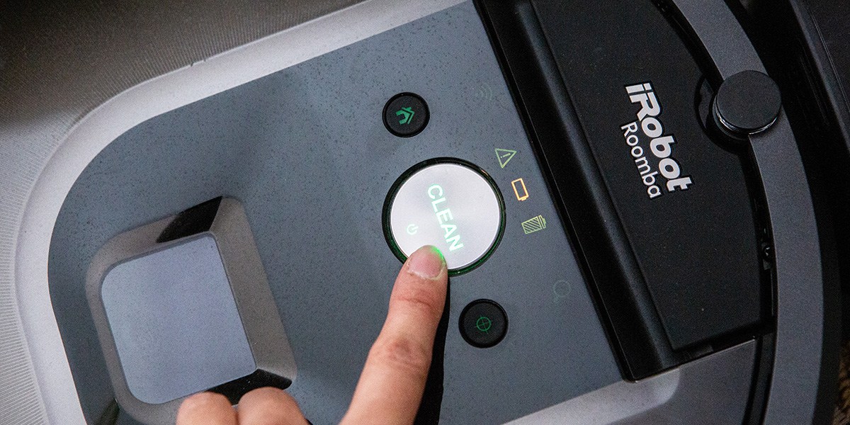 Person touching "Clean" button on Roomba