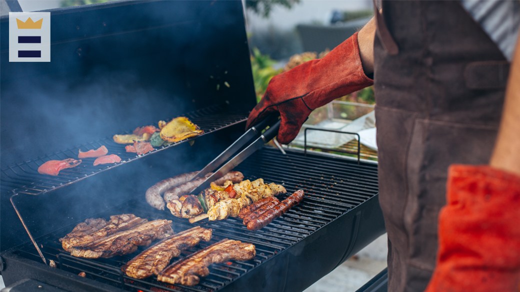 hands of a man grilling meat and sausages