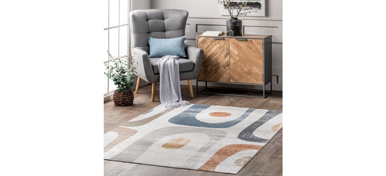 Anthelix Astra Washable Retro Abstract Beige Area Rug on hardwood flooring in front of chair