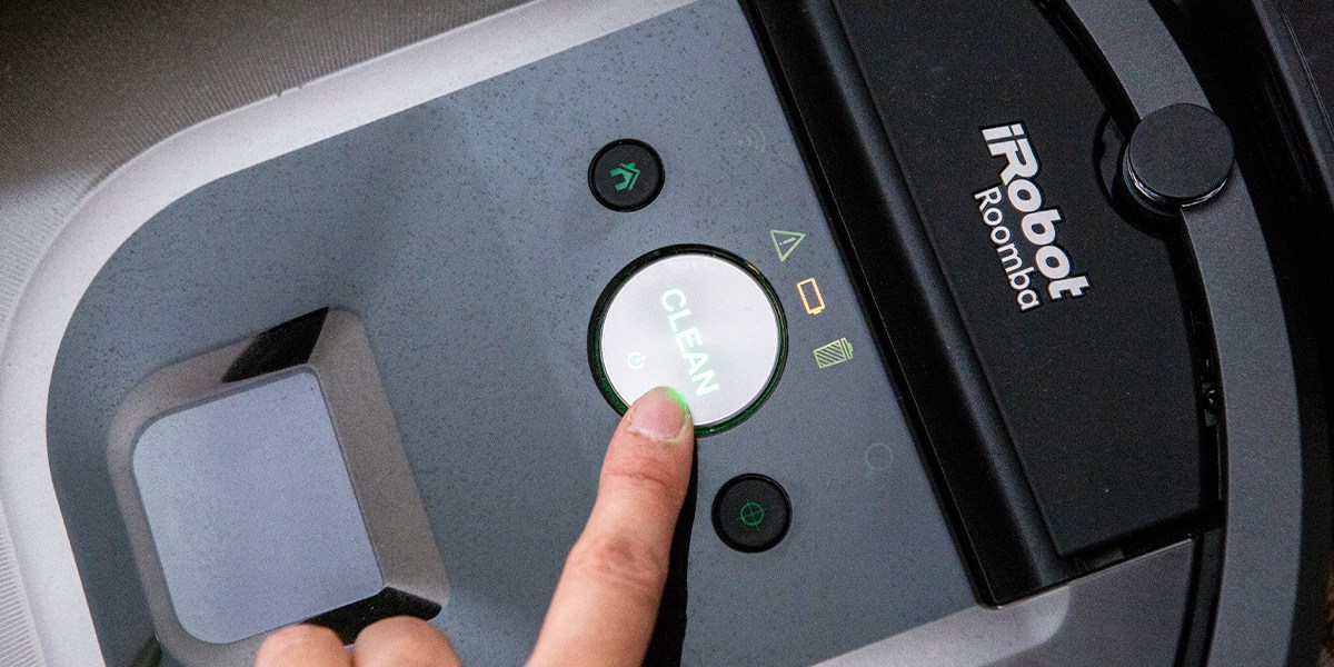 Person pressing "Clean" button on Roomba