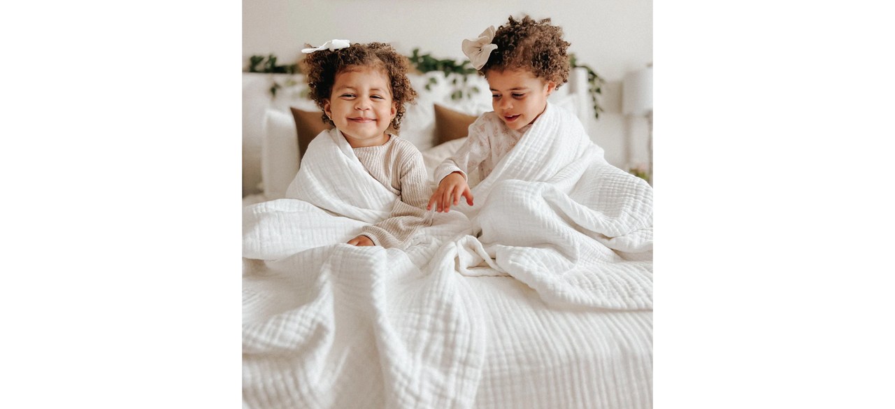 Two children smiling with Muslin Comfort The 365 Blanket