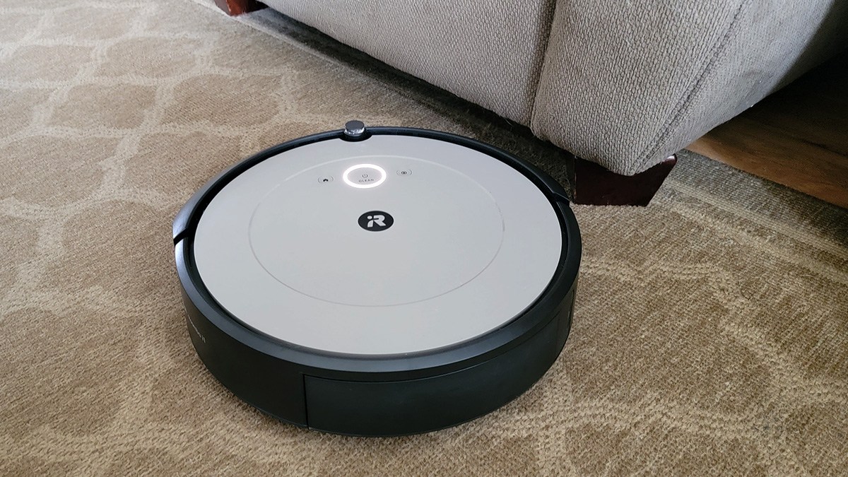 Roomba vacuuming carpet next to sofa