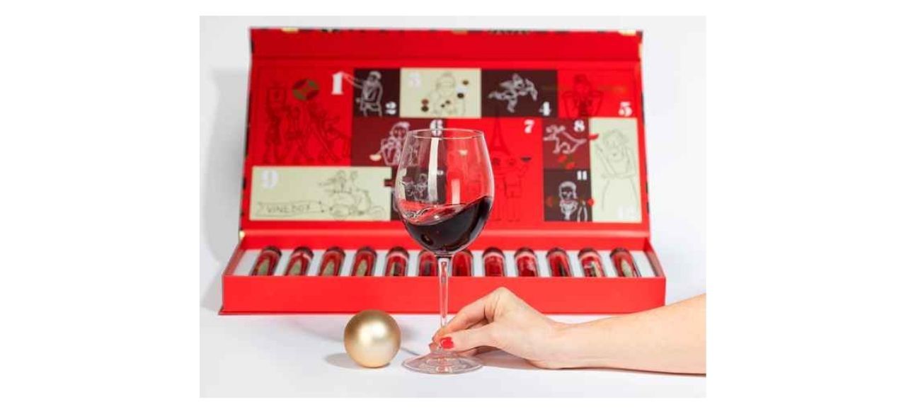 red box with 12 wine samples next to a hand holding a wineglass