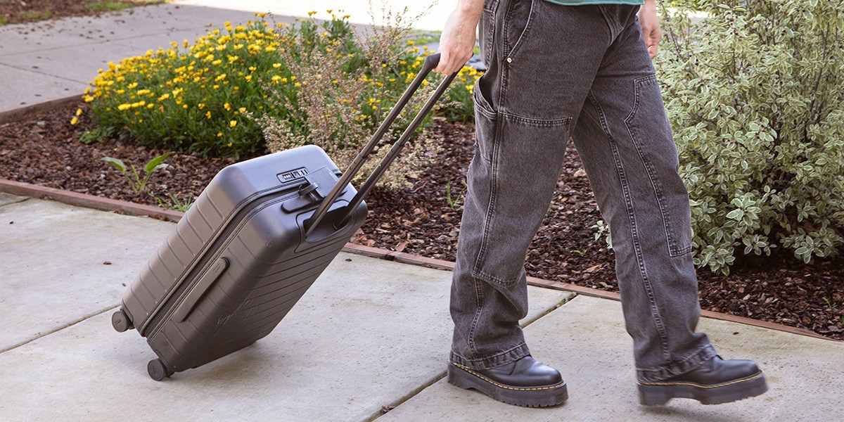 Person rolling suitcase on sidewalk