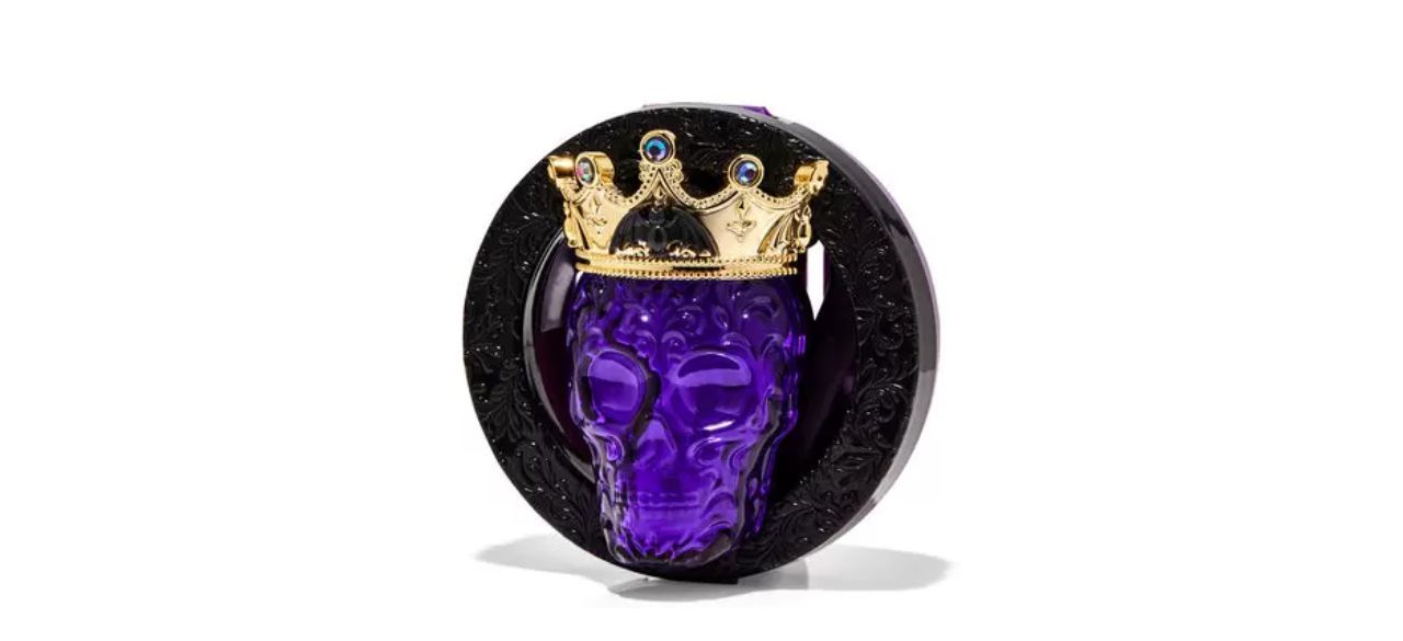 a circular car fragrance holder with a skeleton head sticking out of it, which is wearing a crown