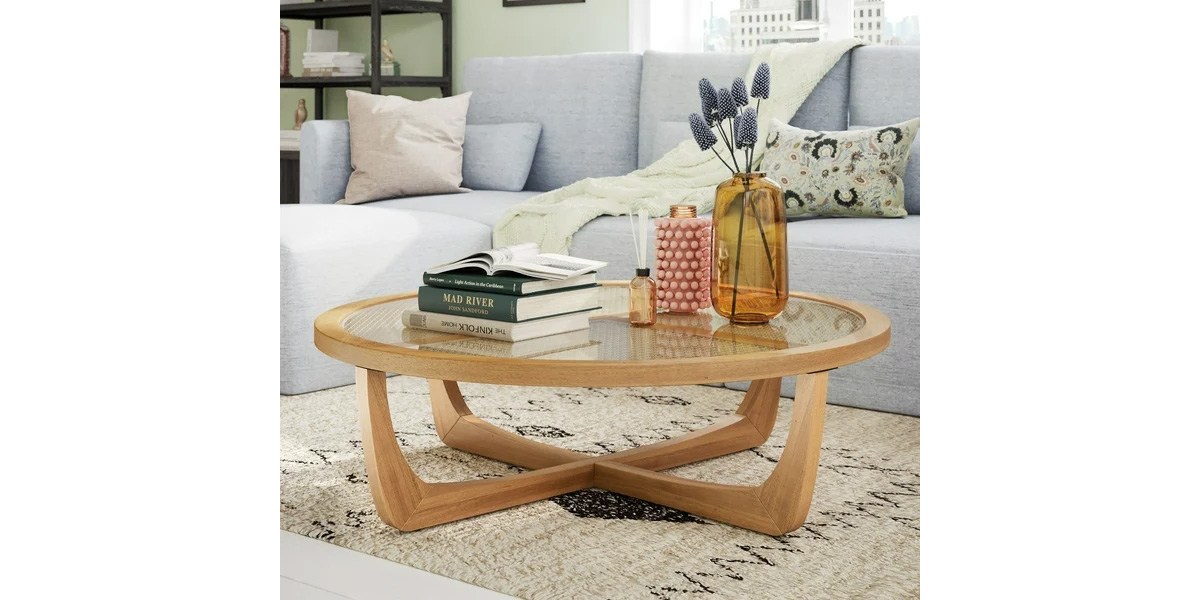 rattan coffee table in a living room with books and plants on it