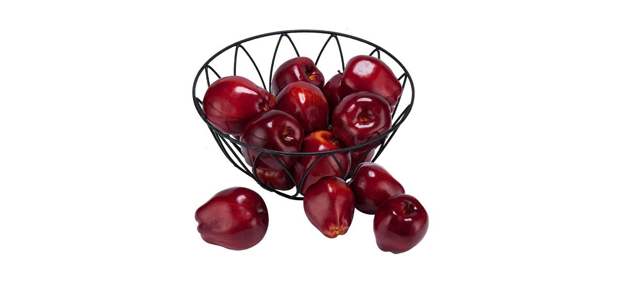 A wire basket full of artificial red apples