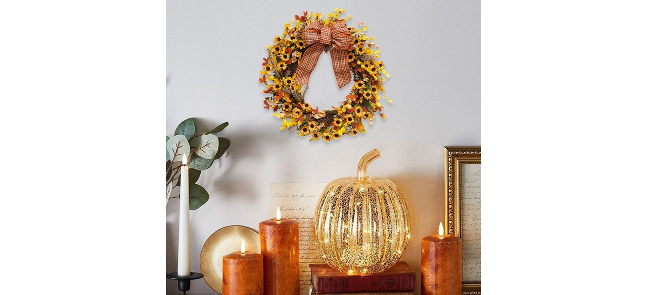 Fall Wreath on wall with fall candles and glass pumpkin on table below