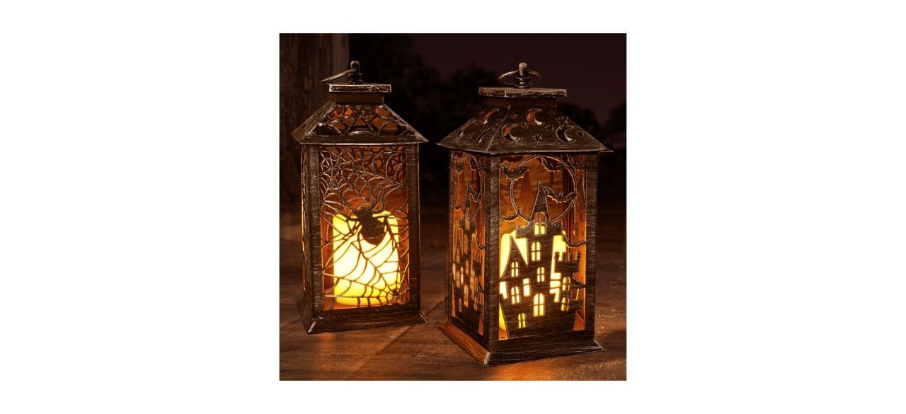 2 Halloween lanterns with images of a spider in a web and a haunted house on the sides