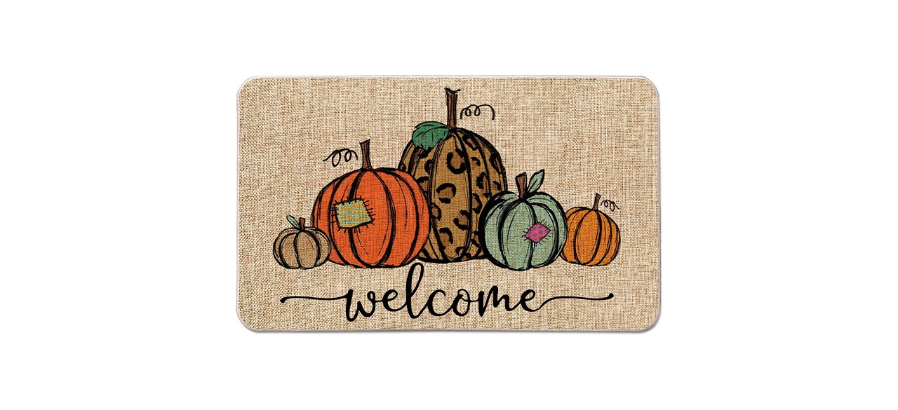 A tan doormat with the word "welcome" on it and designs of orange, tan, cheetah print and green pumpkins on it.