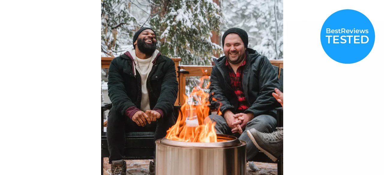 Solo Stove Bonfire 2.0 with fire in it, on a stump, with 2 guys sitting by it outside. Badge on picture says "BestReviews tested."