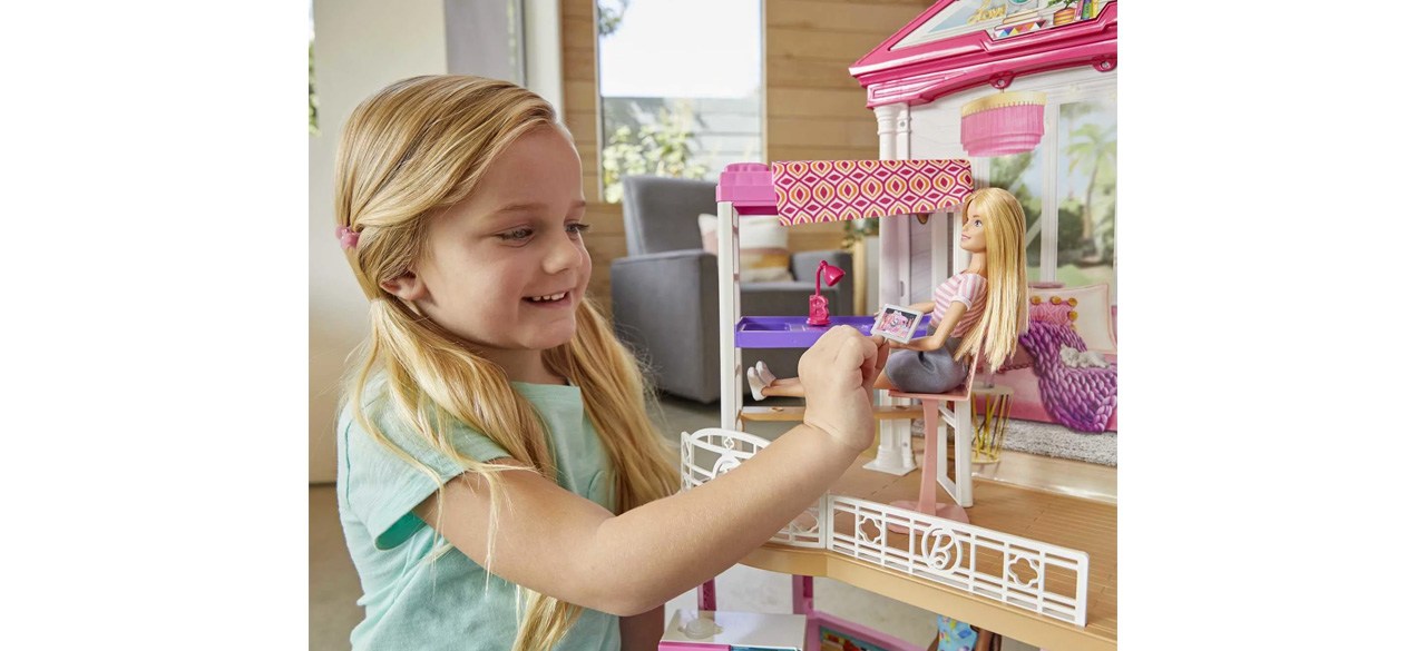 Little girl playing with barbie dollhouse set