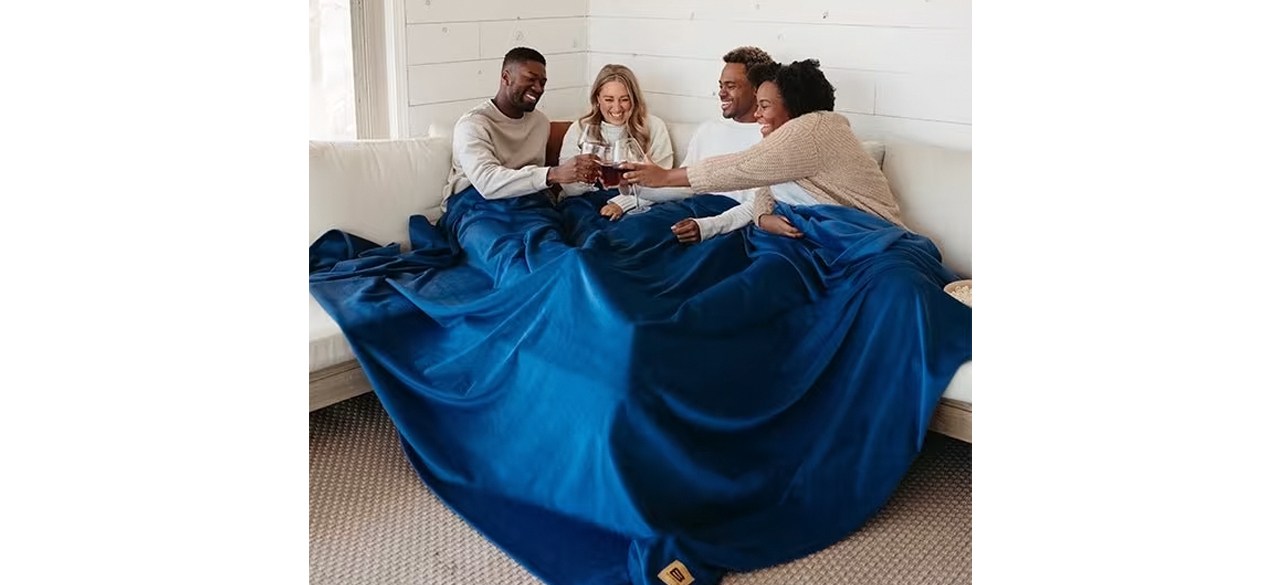 Group of people on sofa sharing Big Blanket Original Stretch Blanket