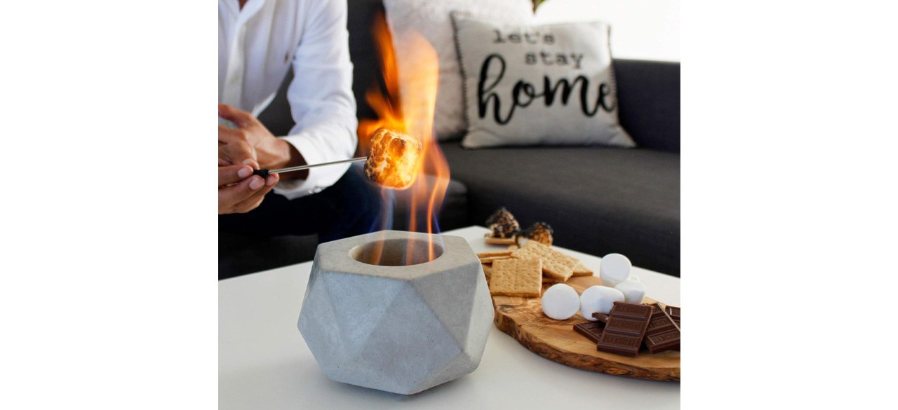 Person roasting marshmallow over indoor firepit