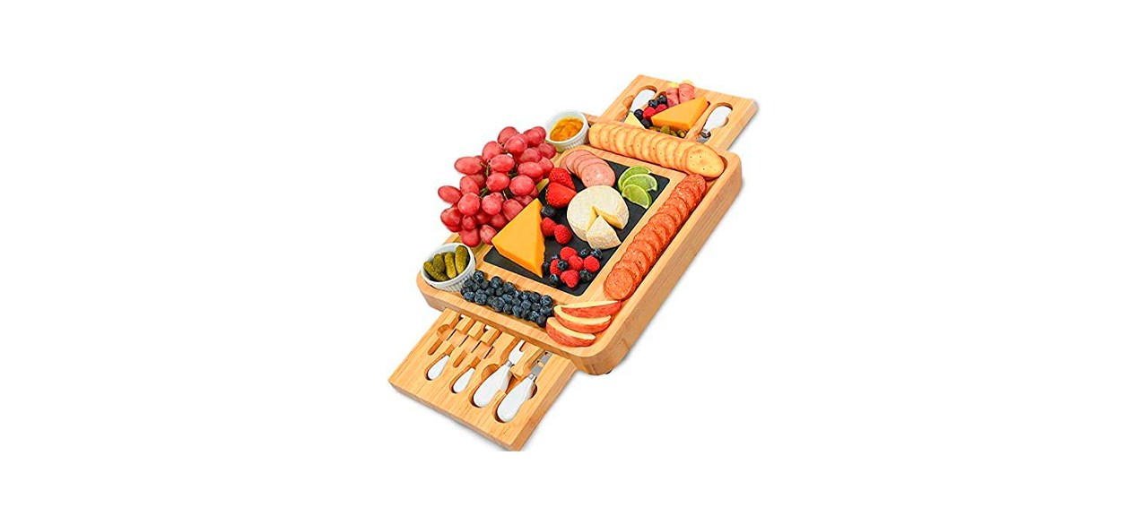 a wooden charcuterie board that has portions that slide out to hold spreading knives and additional snacks