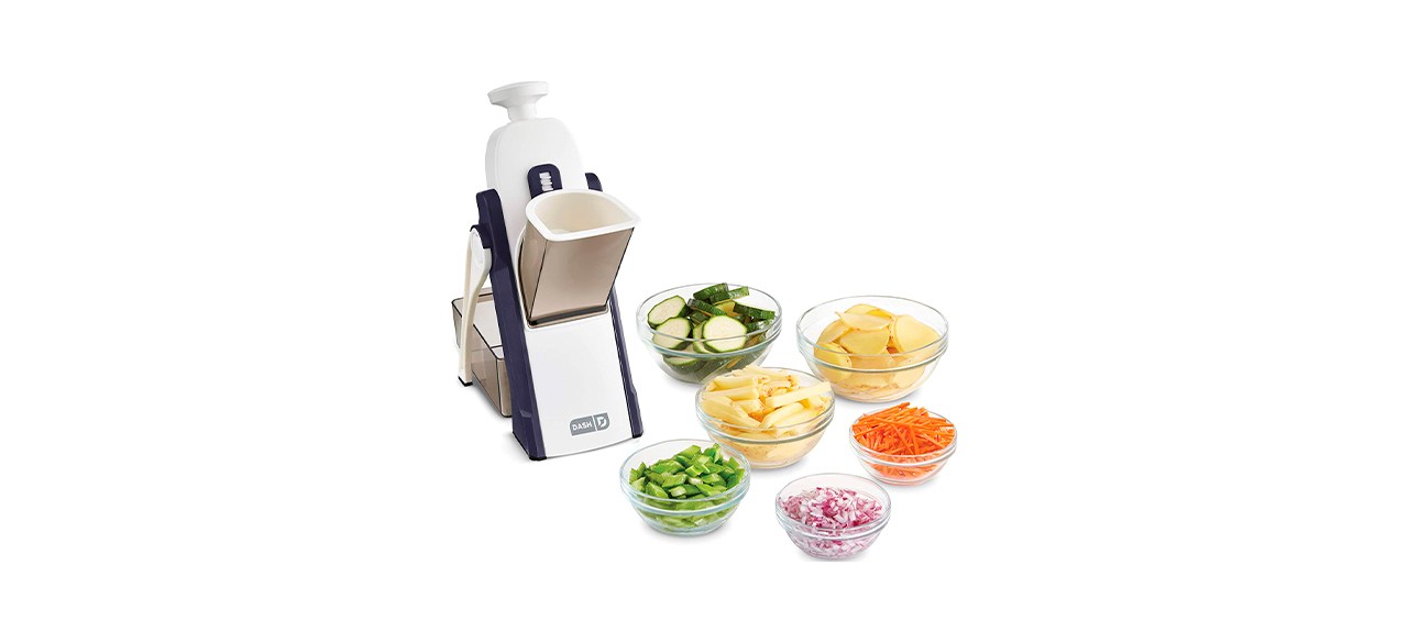 A mandoline slicer shown next to several bowls of cut vegetables