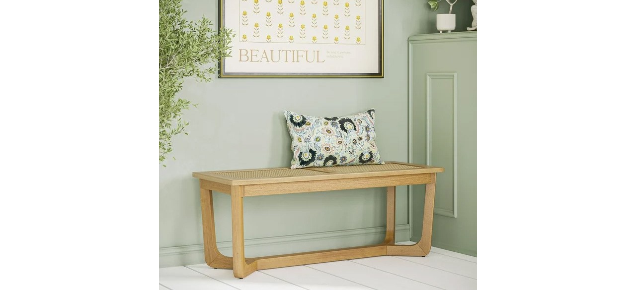 Beautiful wicker and wood bench against sage green wall