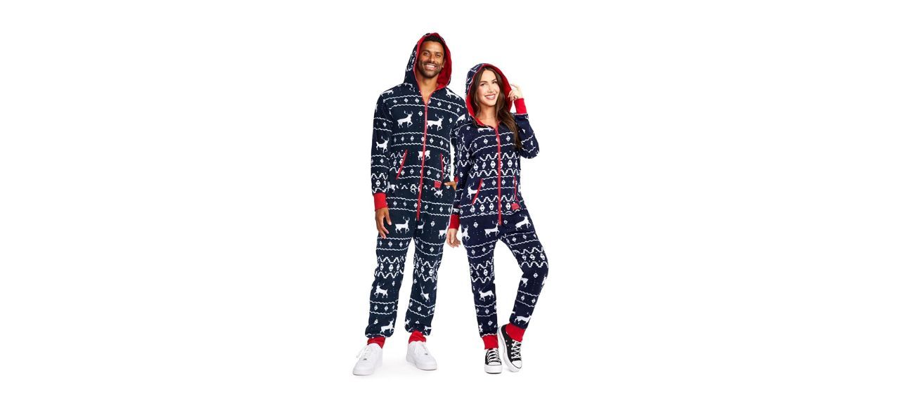 Man and woman wearing Tipsy Elves Matching Christmas Onesies for Adults, navy blue with prints of white reindeer