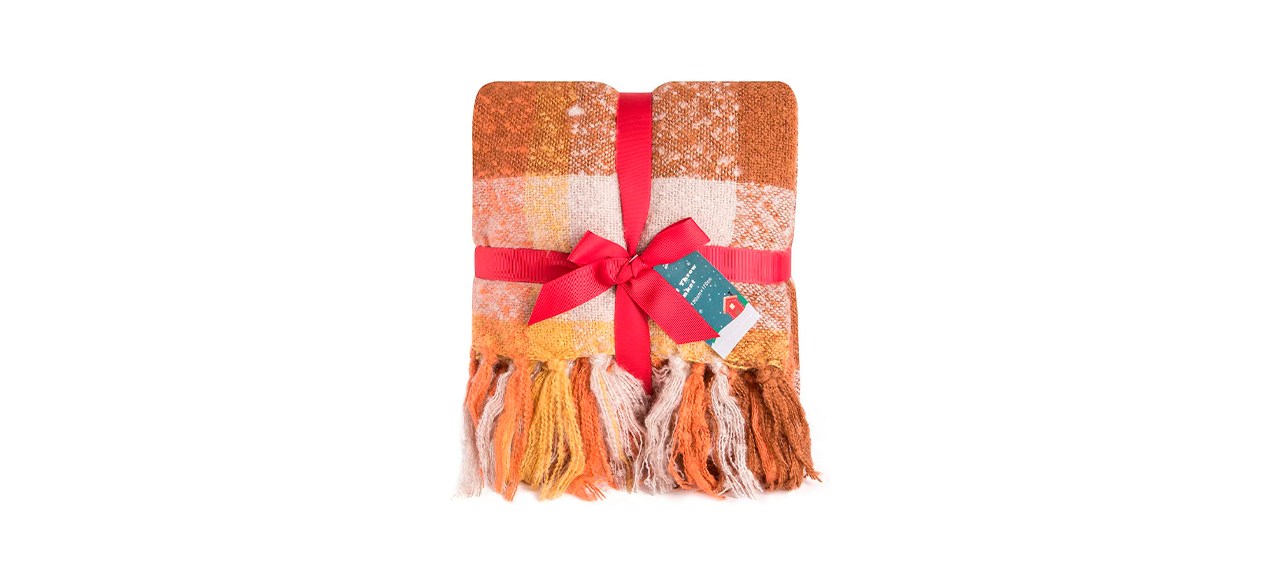 An orange plaid blanket with tassels and various shades of orange and white