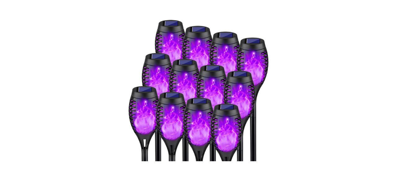 A set of 12 outdoor solar torch lights with purple light inside that looks like it has flames