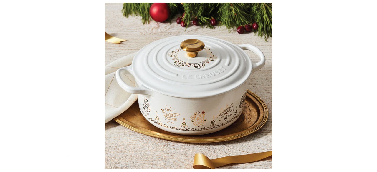 white round Dutch oven with 12 Days of Christmas-inspired gold designs on it