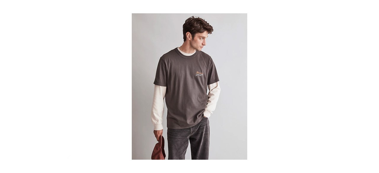 a man wearing a brown t-shirt over a long-sleeved shirt
