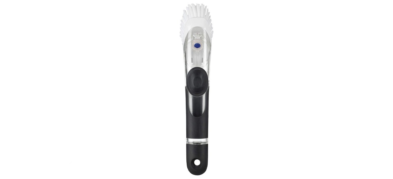 a white and gray dishwashing brush that has an opening in the handle to store dishwashing soap