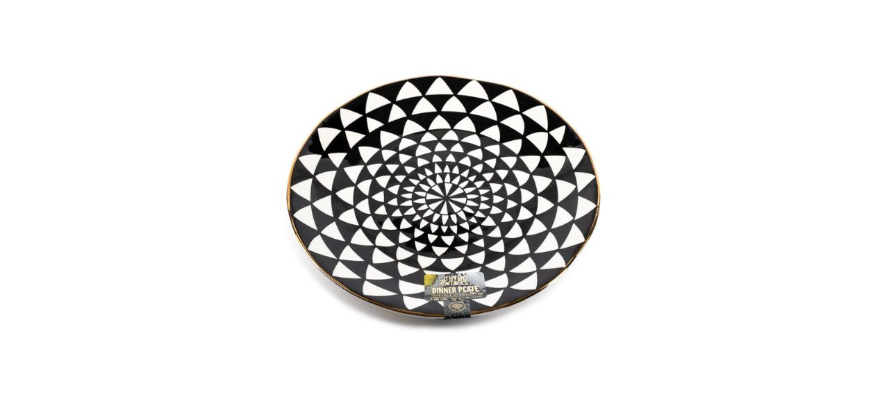 a large dinner plate with black and white circular designs and gold edges