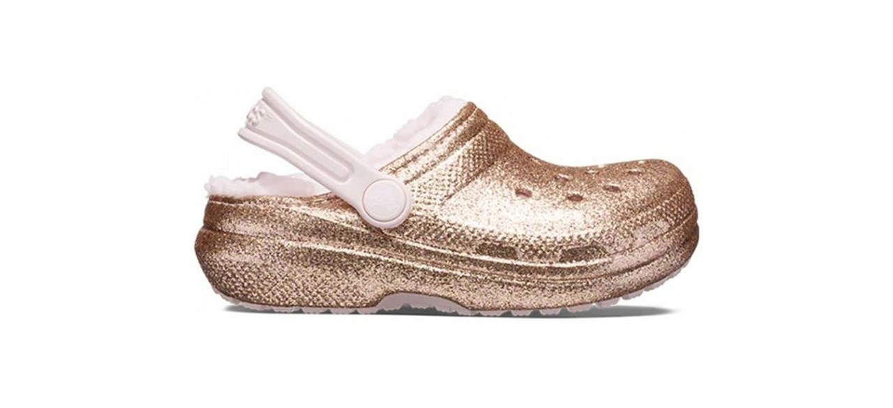 Shiny gold foam clogs with a pink strap on the back and a pink fleece lining