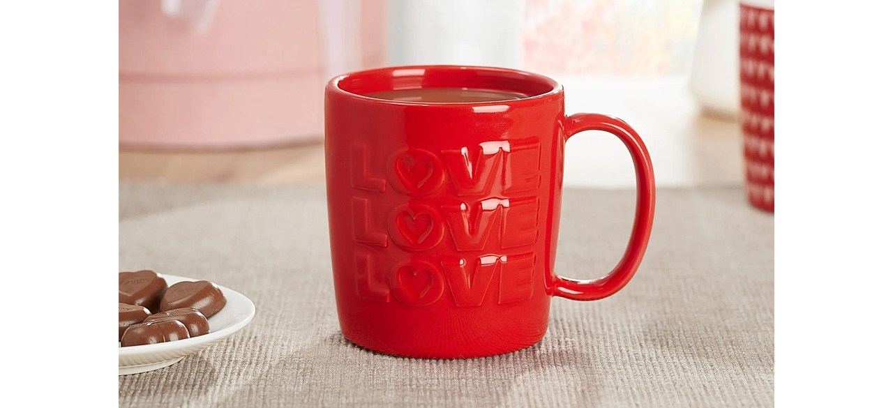 Valentine's Day Red Embossed Love Glazed Ceramic Mug on counter next to plate of chocolate candy