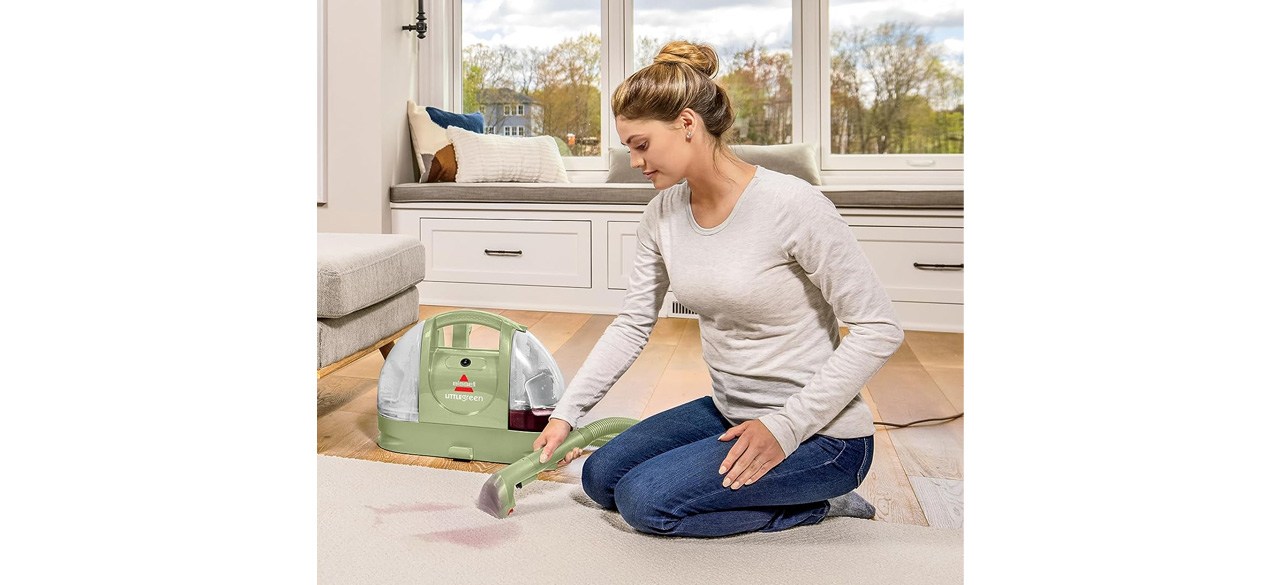 Woman using BISSELL Little Green Multi-Purpose Portable Carpet and Upholstery Cleaner on living room carpet