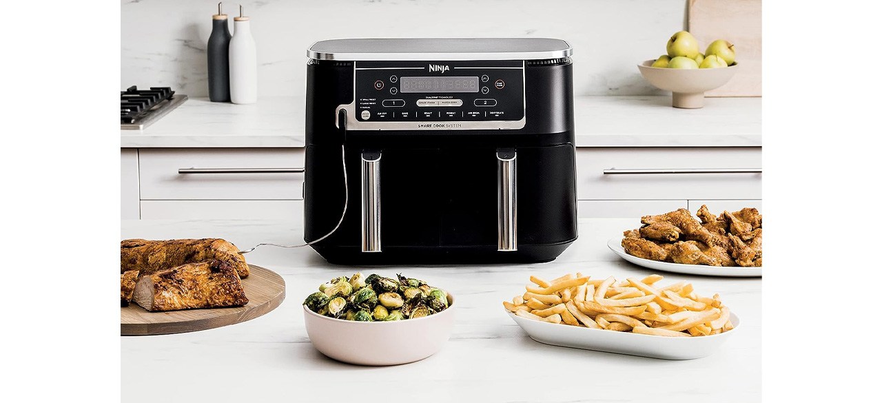 Ninja Foodi 10-Quart 6-in-1 DualZone Smart XL Air Fryer on kitchen counter with cooked food in front