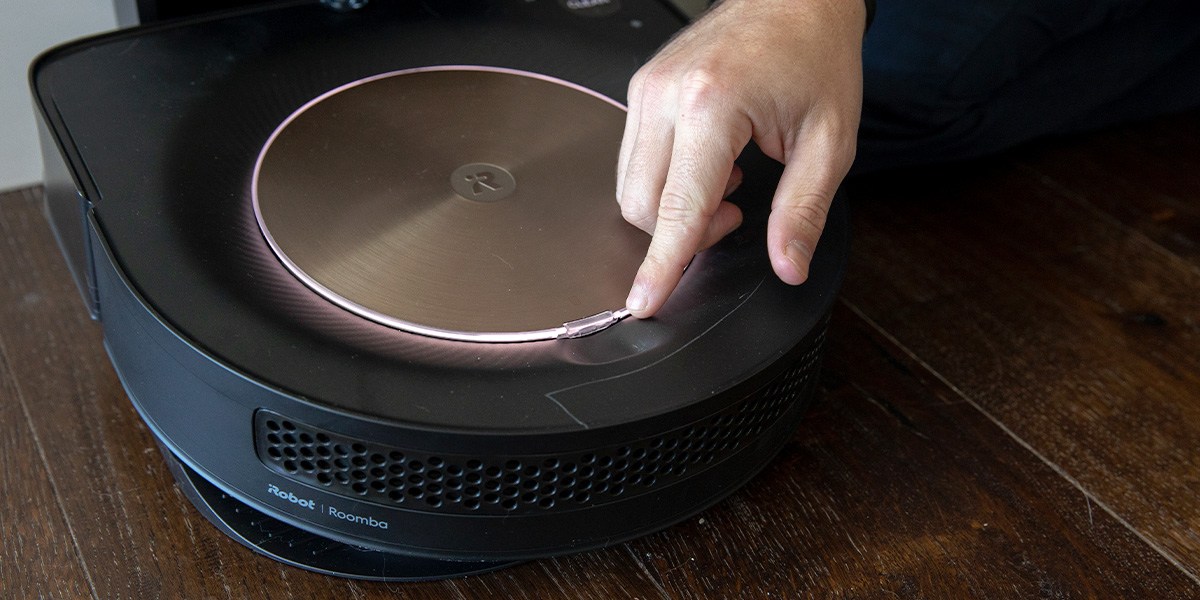 Roomba on charging dock with finger on button