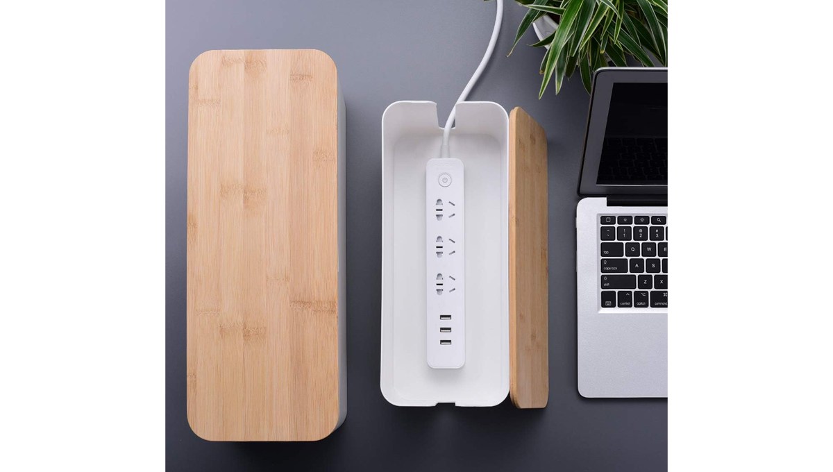 A closed Chouky Large-Cable-Management Box and an open one sit on a desk with a laptop and a plant.