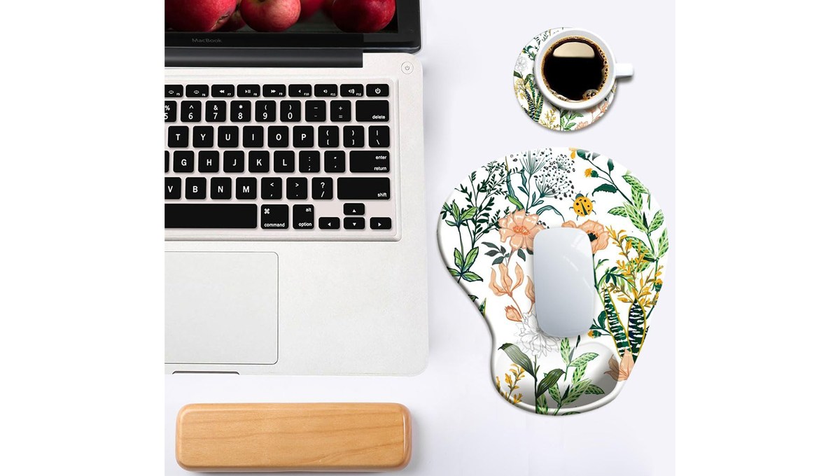 A DOOKE Ergonomic Mouse Pad sits on a table with a laptop, cup of coffee and laptop wrist pad.