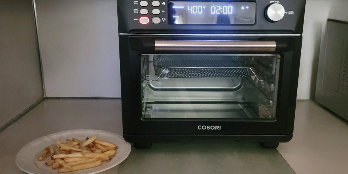 Cosori Smart Air Fryer Toaster Oven on counter with plate of fries in front