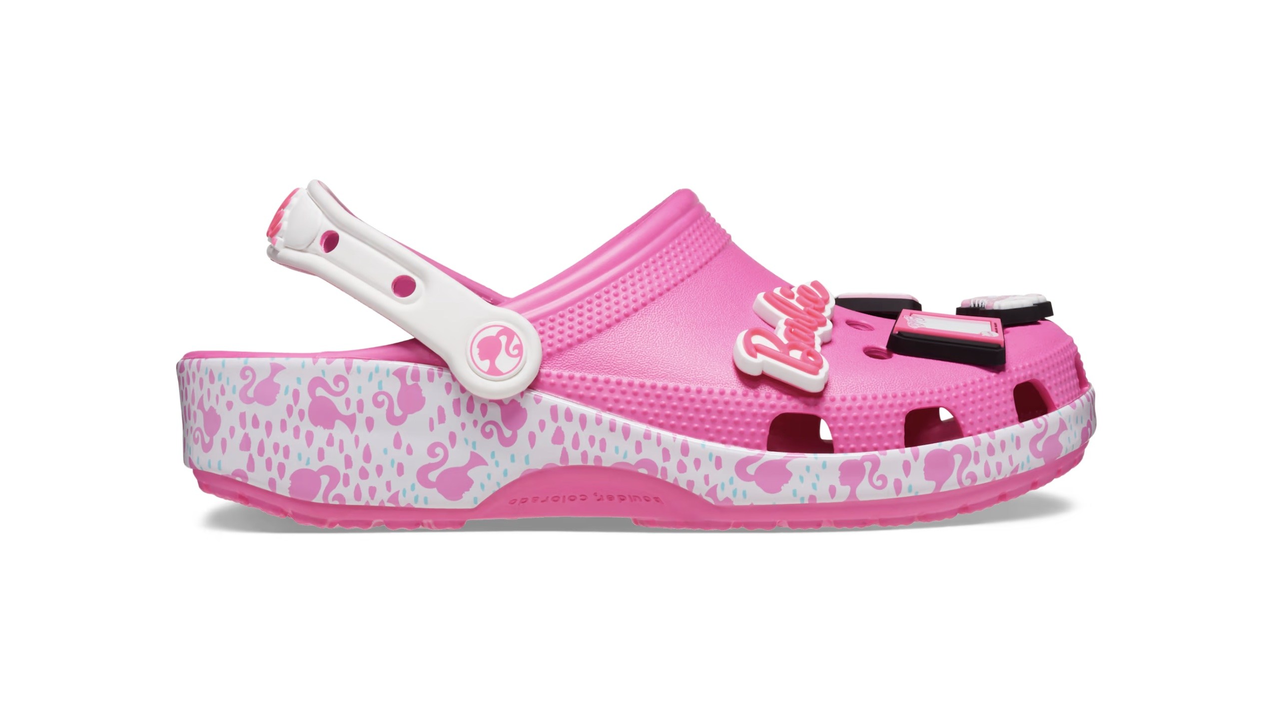 Pink clogs with Barbie-themed Jibbitz attached and a white base with pink Barbie head silhouettes on them.