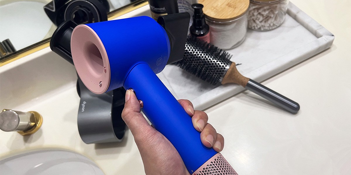 Hand holding blue Dyson Supersonic 