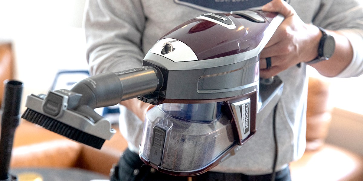 Closeup of person using Shark vacuum with attachment