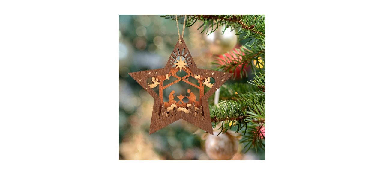 a wooden star-shaped nativity scene ornament hanging on a tree