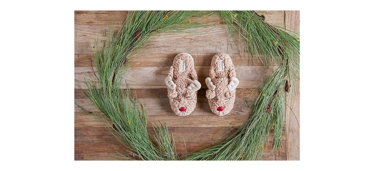 a pair of fuzzy slippers that have antlers and a red nose to make them look like reindeer heads