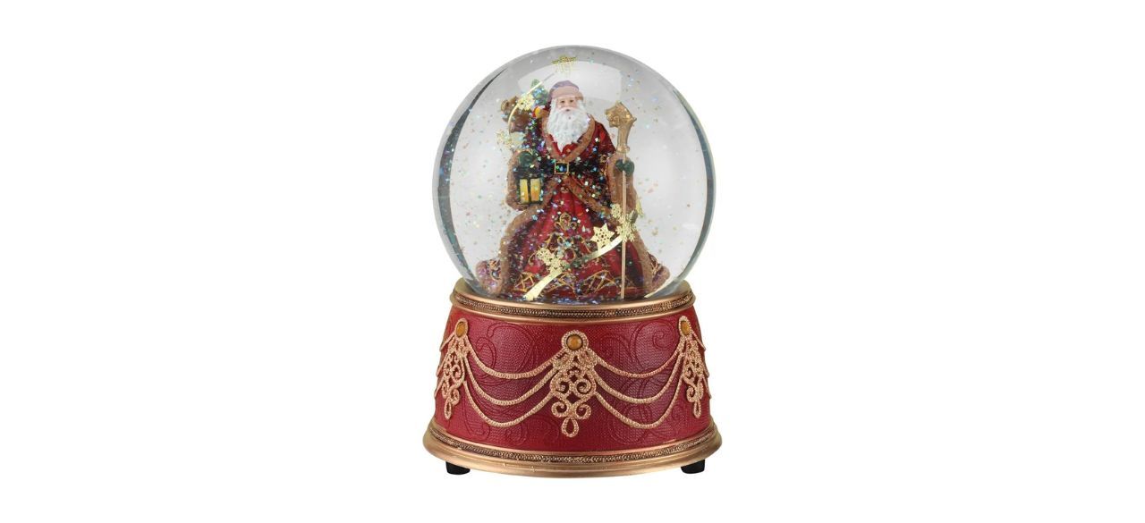 a snowglobe with a red base and a globe with Santa in it holding a lantern and staff