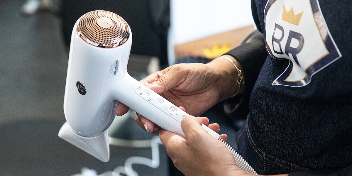 Stylist selects hair dryer heat setting