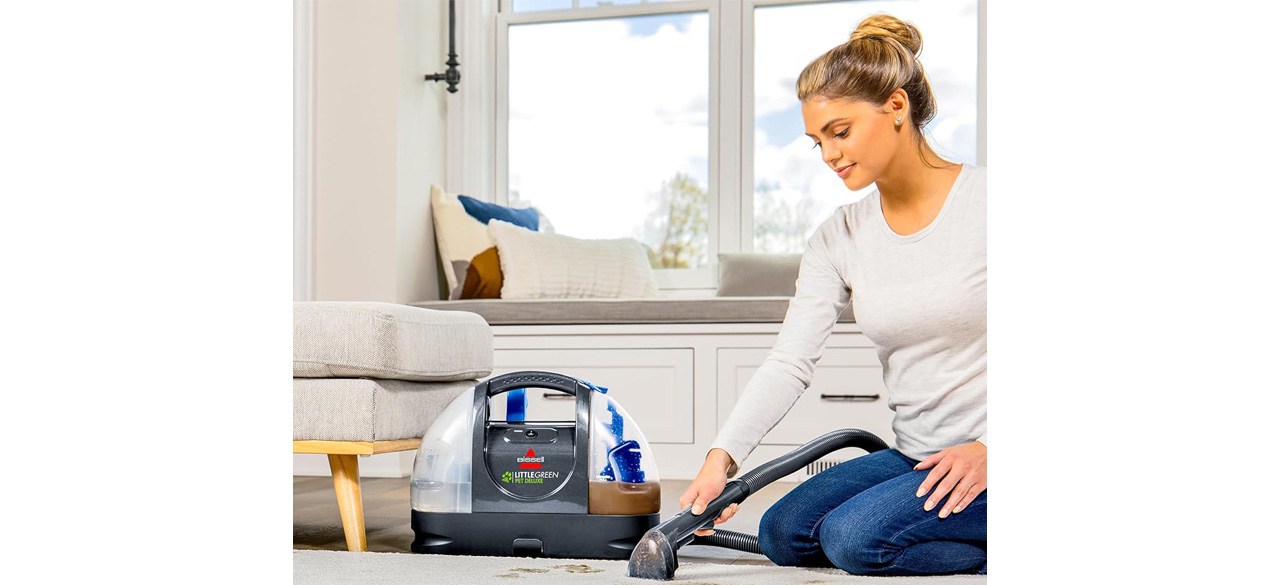 Woman using Bissell Little Green Pet Deluxe Portable Carpet Cleaner on carpet