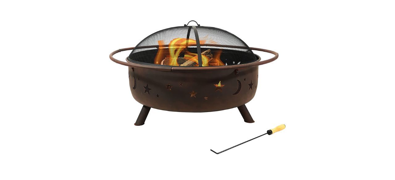 A semi-wide portable fire pit with stars and moons etched on the side and a domed screen on top. There is also a poker.