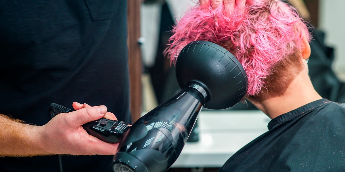 Person getting pink hair styled with diffuser