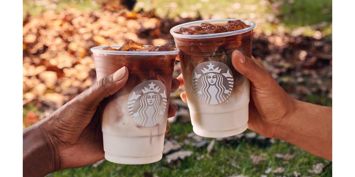 Two people cheering with Starbucks drinks