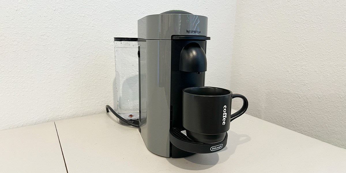 Nespresso VertuoPlus on kitchen counter with black coffee cup