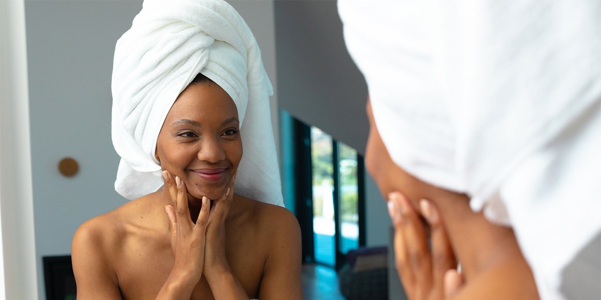 Woman with hair wrapped in towel looking in mirror