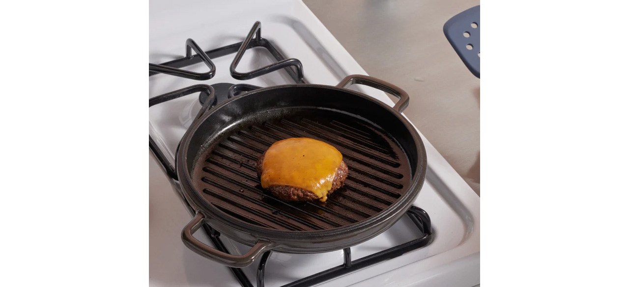 Our Place Cast Iron Hot Grill on stovetop with cheeseburger cooking